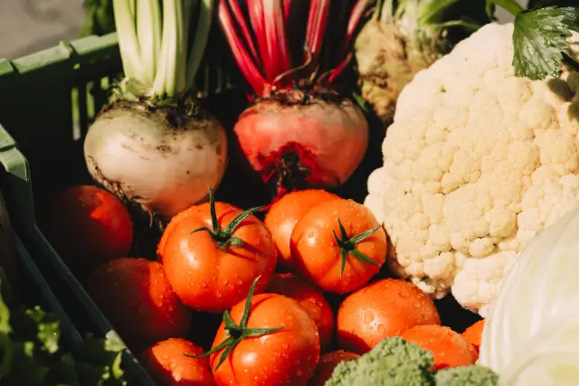 Grüne Kiste mit Tomaten, Randen, Kohlrabi, Blumenkohl und Broccoli